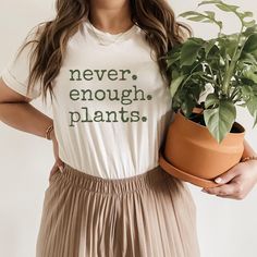 a woman holding a potted plant and wearing a t - shirt that says i can't tonight i have plants