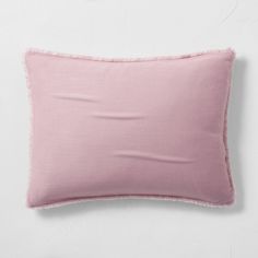 a pink pillow with fray edges on a white wall