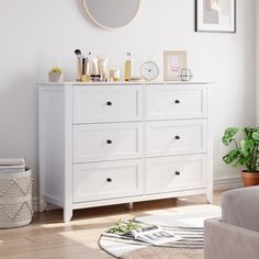 a white dresser with lots of items on top of it and a mirror above it