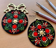 two christmas ornaments sitting on top of a wooden table next to markers and pencils