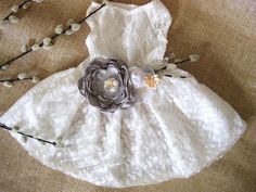 a white dress with flowers on it sitting next to some twigs and twigs