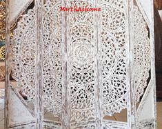 an intricately carved white screen with red writing on the front and bottom corner,