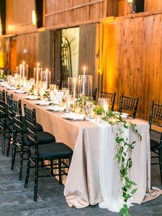 a long table is set up with candles and greenery for an elegant wedding reception