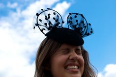 a woman wearing a black and white hat with polka dots on the top, smiling