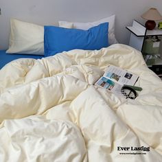 an unmade bed with white sheets and blue pillow cases on the headboard is shown