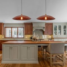 a kitchen with wooden floors and two pendant lights over the island