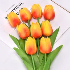 a bunch of orange tulips sitting on top of a piece of white paper