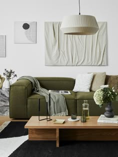 a living room with a green couch and coffee table in front of a painting on the wall