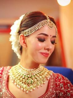 a woman in a red and gold outfit with jewelry on her head, smiling at the camera