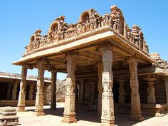 an intricately carved building in the middle of a desert area with columns and pillars