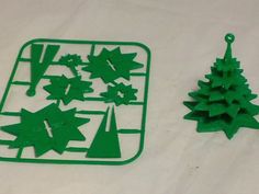 green plastic christmas trees and ornaments on a white tablecloth with a small metal ornament