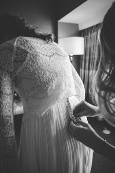 a woman in a white dress is helping another woman with her wedding dress