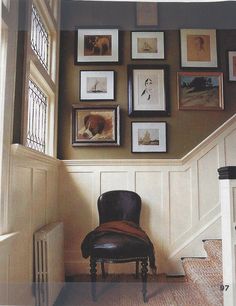 a chair sitting in front of a bunch of pictures on the wall next to a doorway