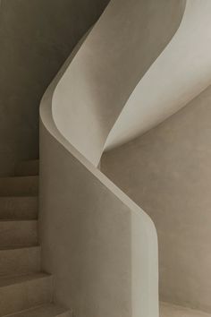 a white spiral staircase next to a wall