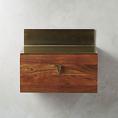 a wooden box with a metal lid on the top is hanging from a wall in front of a white wall