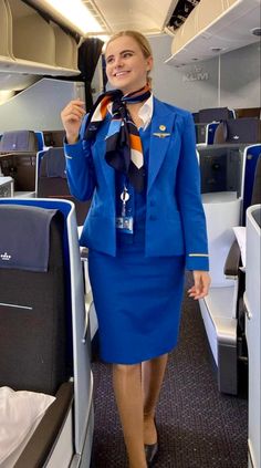 a woman in a blue suit is holding up an airplane's necktie and smiling