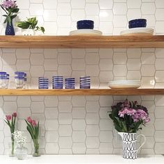 vases and bowls on shelves in a kitchen with white tile backsplashing