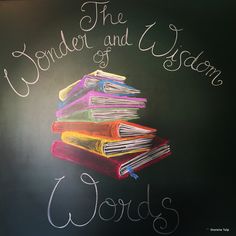 a chalkboard with the words wonder and vision written on it in front of a stack of books