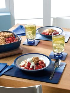 a wooden table topped with plates of food and glasses of water on top of it