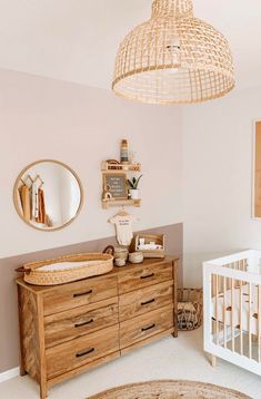 a baby's room with a crib, dresser, and mirror on the wall