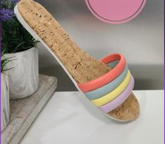 a pair of colorful corked sandals sitting on top of a table next to a potted plant