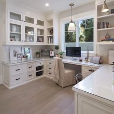 a home office with lots of white cabinets and desks in the middle of it