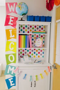 a colorful welcome sign hanging from the side of a white bookcase