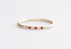 a white gold ring with three red stones on the inside and outside, sitting on a plain surface