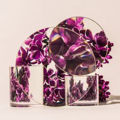 three mirrors with purple flowers in them on a table