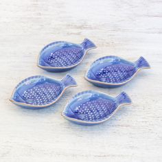 three blue fish shaped dishes sitting on top of a table