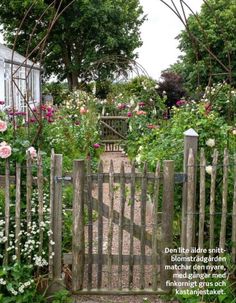 a wooden gate surrounded by flowers and greenery