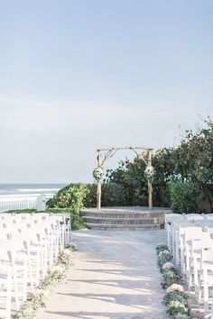 an outdoor ceremony set up with white chairs