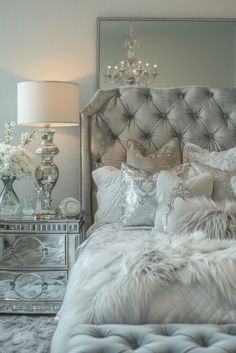 a bedroom with a bed, mirror and chandelier on the wall next to it