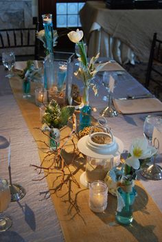 the table is set with candles, flowers and vases for dinner guests to enjoy