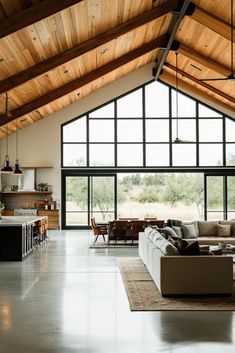 a large open living room with high ceilings and wooden beams on the ceiling is filled with furniture