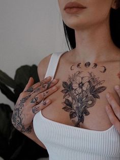 a woman with tattoos on her chest is holding her hands to her chest and looking at the camera