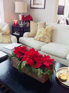 a living room filled with white couches and poinsettis on top of a coffee table