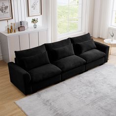 a black couch sitting on top of a wooden floor next to a white rug in a living room