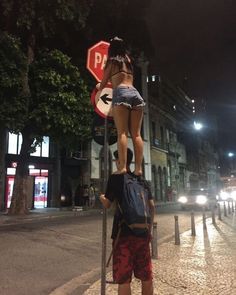 a woman standing on top of a man's head while holding a stop sign