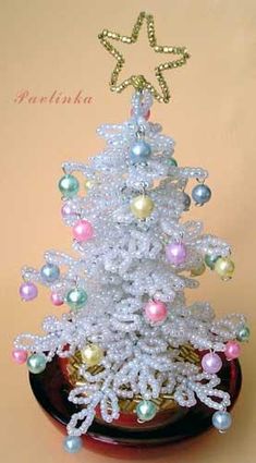 a small white christmas tree with pearls on it's branches and snowflakes