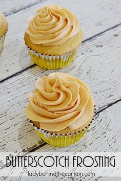 three cupcakes with frosting sitting on top of a wooden table next to each other