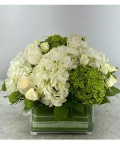 a vase filled with white and green flowers on top of a marble countertop next to a wall