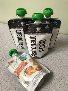 three baby food pouches sitting on top of a counter next to a bag of fruit