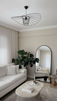 a living room with white couches and a large mirror on the wall above it