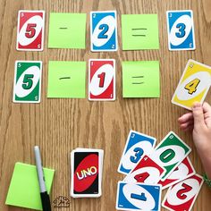 someone is playing with the numbers and signs in their hands on a wooden table next to green sticky notes