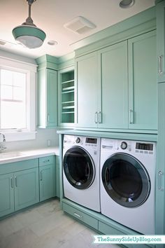 a washer and dryer in a green laundry room with stairs leading up to the second floor