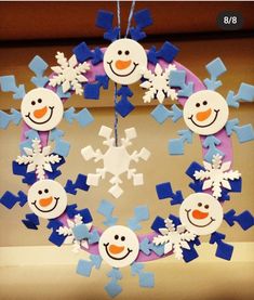 a wreath made out of snowflakes and paper snowmen is hanging from the ceiling