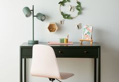 a desk with a chair, lamp and pictures on the wall