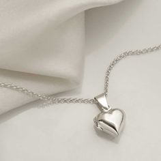 Keep this silver tiny heart locket close to your heart. This beautiful small sterling silver heart locket is totally adorable - a wear everyday favourite! This locket also makes a wonderful bridesmaids gift especially when personalised with a letter charm. Add your personal touch to this silver locket, by adding a tiny sweet photograph, a lock of hair, or a small hand written note inside. Add a further key and pearl charm, and/or letter charm to the locket to create a fashionable cluster necklac Elegant Silver Heart Locket Necklace, Silver Heart Locket Necklace Gift, Heart Shaped Hallmarked Silver Locket Necklace, Heart-shaped Sterling Silver Locket Necklace For Weddings, Silver Heart-shaped Locket Necklace With Adjustable Chain, Silver Heart Locket, Lock Of Hair, Sterling Silver Locket, Silver Locket