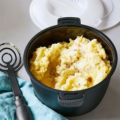 mashed potatoes in a pot with a spatula next to it on a table